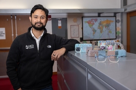 Faraz Faruqi stands next to colorful and texturized objects created by TactStyle, including eyeglass frames, a phone case, a pot, and picture frame.