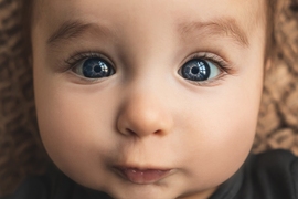 Photo of a baby's face with big blue eyes that don't quite seem perfectly focused yet