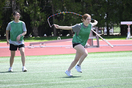 Two students on MIT's playing fields. One appears to be running with a jumprope.