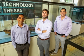 Anthony Valiaveedu, Nat Edmonds, and Jose Izurieta stand in front of ship displays in MIT's Hart Naval Gallery