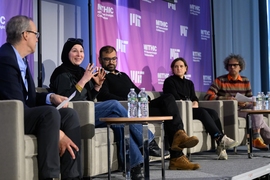 Five people are on a stage talking as part of a panel discussion