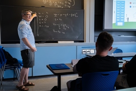 Michael McDonald stands at a chalkboard, lecturing in a classroom