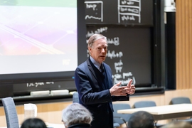 Nicholas Burns stands in front of audience, speaking at seminar