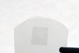 The researchers' membrane, consisting of graphene on a polycarbonate track etch membrane (the graphene is the darker region in the center of the white film). The total membrane is about 2 cm wide by 1 cm tall, while the graphene portion is about 5 mm by 5 mm.