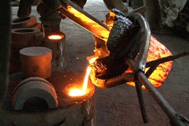 D-Lab Scale-Ups fellow Kwami Williams ('12) and Ghanaian master blacksmith Stone Musah at work in Ghana pouring molten cast iron into a mold to create an auger. The auger was incorporated into a press used to extract oil from Moringa seeds.