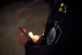 An MIT Police officer’s badge is illuminated by candlelight.