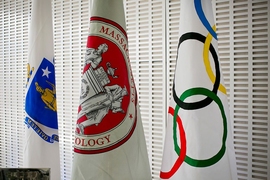 Three flags on poles: Massachusetts state, MIT, and Olympics