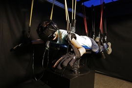 A user experiences the underwater world using Amphibian SCUBA diving simulator. The user is resting on a suspension system wearing Oculus Rift, a snorkel with breathing sensor, and gloves for motion detection. 