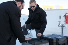 Professor Michael Strano (left) and graduate student Anton Cottrill check on their test device on the roof of an MIT lab building.
