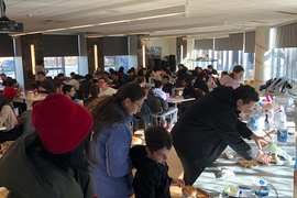 People wait in line for food at a popular event indoors.