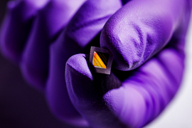 A close-up of the tiny square material has a black square in middle that reflects gold, with translucent border.