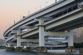Curved split-level road bridge stands in water beside tall apartment buildings