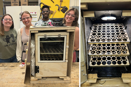 Four students stand in front of wooden laser cut box.