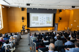 A full auditorium watches a slide show by John Hart.