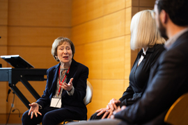Suzanne Berger speaks to two people on stage.
