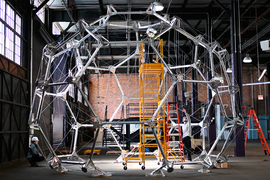 People in a warehouse building a large dome-like habitat