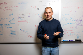 Phillip Isola portrait in front of a math-filled white board.