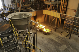 A wide photo of the plant shows large machinery on the second floor and molten steel flowing on the first.