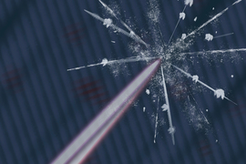 A laser beam hits a surface, causing a glass-like crack with white particles.