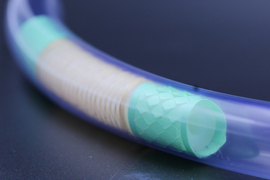 Closeup photo of a tiny, long tube with teal material inside.