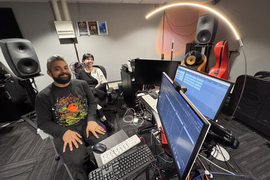 Two people in a music studio working on computers.
