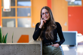 Veronica Sosa portrait in MIT building lobby, with plants and orange walls.