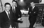 Professors Yet-Ming Chiang (left), Gerbrand Ceder (center) and Donald Sadoway have developed a new material for rechargeable batteries, which Dr. Chiang holds in his left hand. Behind them is the apparatus used to test the new batteries against old ones.