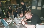 Shannon Cheng (left foreground), a senior in aeronautics and astronautics, and Steve Sell, a consultant for Payload Systems, Inc., troubleshoot a satellite built by students and staff at MIT and about to be tested in NASA's KC-135.