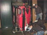 Workers load the car into an elevator shaft.