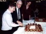 Beth Ingram and Professor Vernon Ingram cut the cake at the Ashdown House dinner in their honor as graduate student Jennifer Farver looks on.