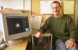 Simon Portegies Zwart rests his right hand on a prototype of the GRAPE-6, a computer he'll use to simulate star clusters (seen on monitor) and galactic nuclei.