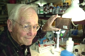 Professor Vernon Ingram holds up cell cultures  that he and senior technical associate Barbara Blanchard have worked with during  their research on the beta-amyloid plaques that attack the brains of Alzheimer's  patients.