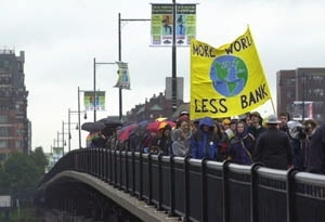 Activists cross the Massachusetts Avenue bridge from Boston to Cambridge to protest the policies of the World Bank during MIT's Commencement .
