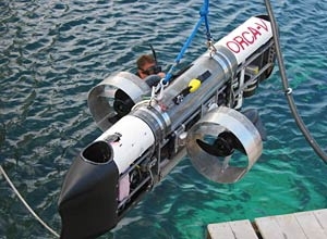 The six-foot-long ORCA-V has two main thrusters  at the side and two vertical thrusters at the bow and stern. There are two main  dry compartments in the sub; the top one contains a computer that controls the  sub, while the bottom one contains the batteries and the motor drivers.