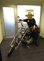 Kimberly Shooter, chief marketing officer for the MIT Federal Credit Union, tries out the Harley-Davidson motorcycle to be raffled.
