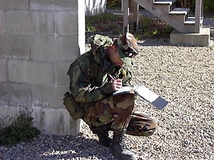 Cadet Battalion Commander Aneal Krishnan hunkers down to write an evaluation of a cadet's performance during fall field training exercises at Camp Edwards on Cape Cod.