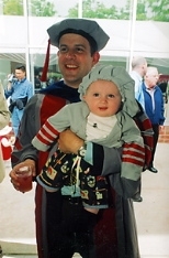 Six-month-old Miles Fox-Kempler, all dressed up in toddler-sized MIT regalia, relaxes in his father's arms at the hooding ceremony. Baylor Fox-Kemper received the Ph.D. in physical oceanography.