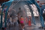 Children combat the day's heat and humidity by cooling off in a water spray tent provided by Boston Emergency Medical Services.