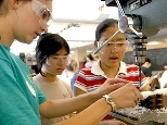 Joelle Brichard, a resident tutor and MIT student, assists Women's Technology Program high school students Helen Deng San Francisco, center, and Julia Chang of Torrance, Calif., as they build a part for a motor.