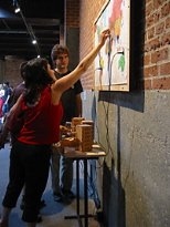 Exhibit visitors play with Rahul Bhargava's interactive piece "Drums of War."