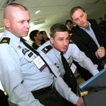 "TacShot" team leader Andrew Heafitz, right, looks on as Army Command Sergeant Major Michael Kelso, left, and Colonel Ernest Forrest, judges at the Soldier Design Competition, review project submissions.