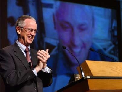 MIT President Charles Vest welcomes Lt. Col. Mike Fincke, whose live image from aboard the International Space Station is projected behind him, to Fincke's 15th-year MIT reunion in Kresge Auditorium.