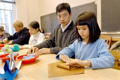 (Right to left) Claire Sawayanagi, 8, Junichi Sawayanagi and Sarah Sawayanagi, 11, drove from West Barnstable to attend the origami workshop. Claire is using the wet-folding technique, where the heavy paper is dampened with a cloth to give it a leathery consistency that is easier to work with. She's making the third and final duck form of the day.