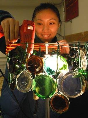 Rene Chen, a sophomore in materials science and engineering, makes an intriguing lamp out of jagged jar bottoms as she "up-cycles" trash into art.