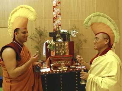 Adorned with hats to show discipleship, MIT Chaplain Tenzin L.S. Priyadarshi, left, and Lama Dhondup Tsering ring ceremonial bells representing compassion at Simmons Hall Monday in the room where the sand mandala is on display.