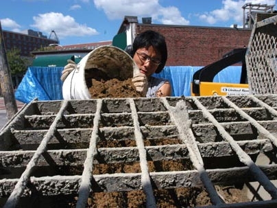 A team of MIT architecture students built a wall behind the MIT Museum by following an ancient construction technique known as "rammed earth." Here, graduate student Shuji Suzumori prepares the mixture of Boston Blue Clay, sand and gravel that was used to build the wall.