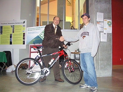 Environmental Health and Safety Director Bill Van Schalkwyk, left, celebrates with Simcha Singer, a graduate student in mechanical engineering, who won the 2004 transportation survey grand prize, a Giant Rincon mountain bike.