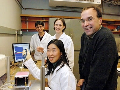 A team of MIT researchers is working on an implantable chip that can track whether a person is responding to cancer chemotherapy treatment. Standing, from left to right, are graduate student Christophoros Vassiliou, graduate student Karen Daniel and Michael Cima, professor of materials science and engineering. Seated in front is graduate student Grace Kim.