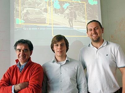 Tomaso A. Poggio, professor of Brain and Cognitive Sciences (left), and postdocs Thomas Serres and Stanley Bileschi (right), stand in front of a street scene.