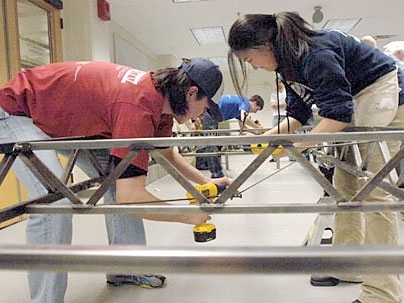 Members of MIT's regional Steel Bridge Competition team replicated their high-speed construction at a department celebration of their victory. Shown in the photo are junior Tracy Takemura, right, and sophomore Jose Cano, left. Quinn Vollmert, a junior, is in blue T-shirt at back.